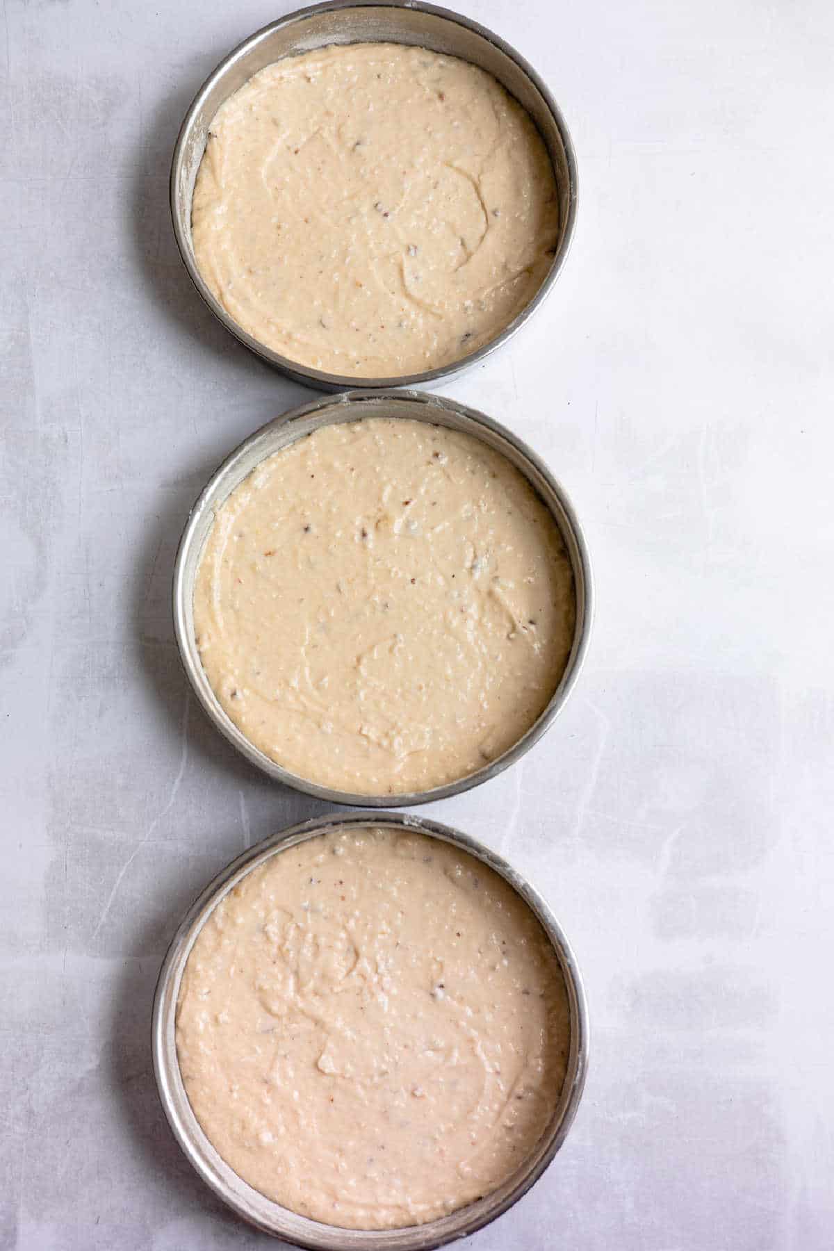 Three cake pans filled with Italian cream cake batter. 