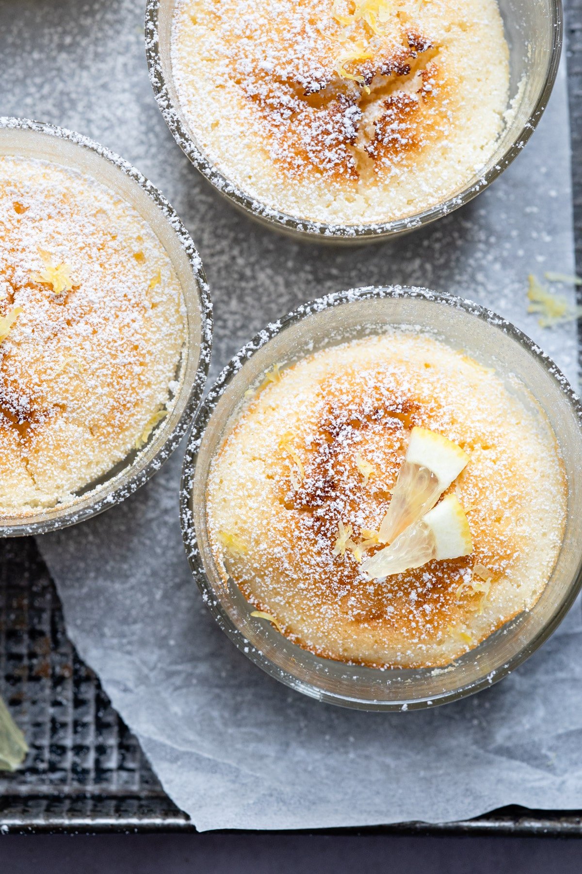 Closeup photo of a lemon pudding cake with a piece of cut lemon on top. 