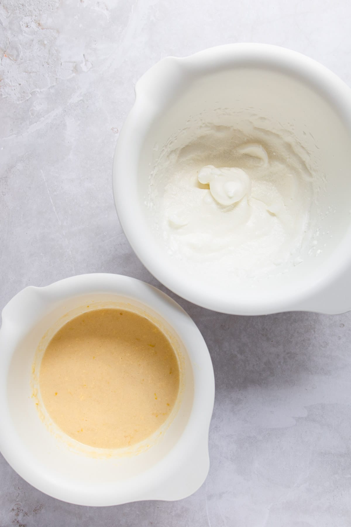 Wet and dry ingredients for lemon pudding cake in mixing bowls. 