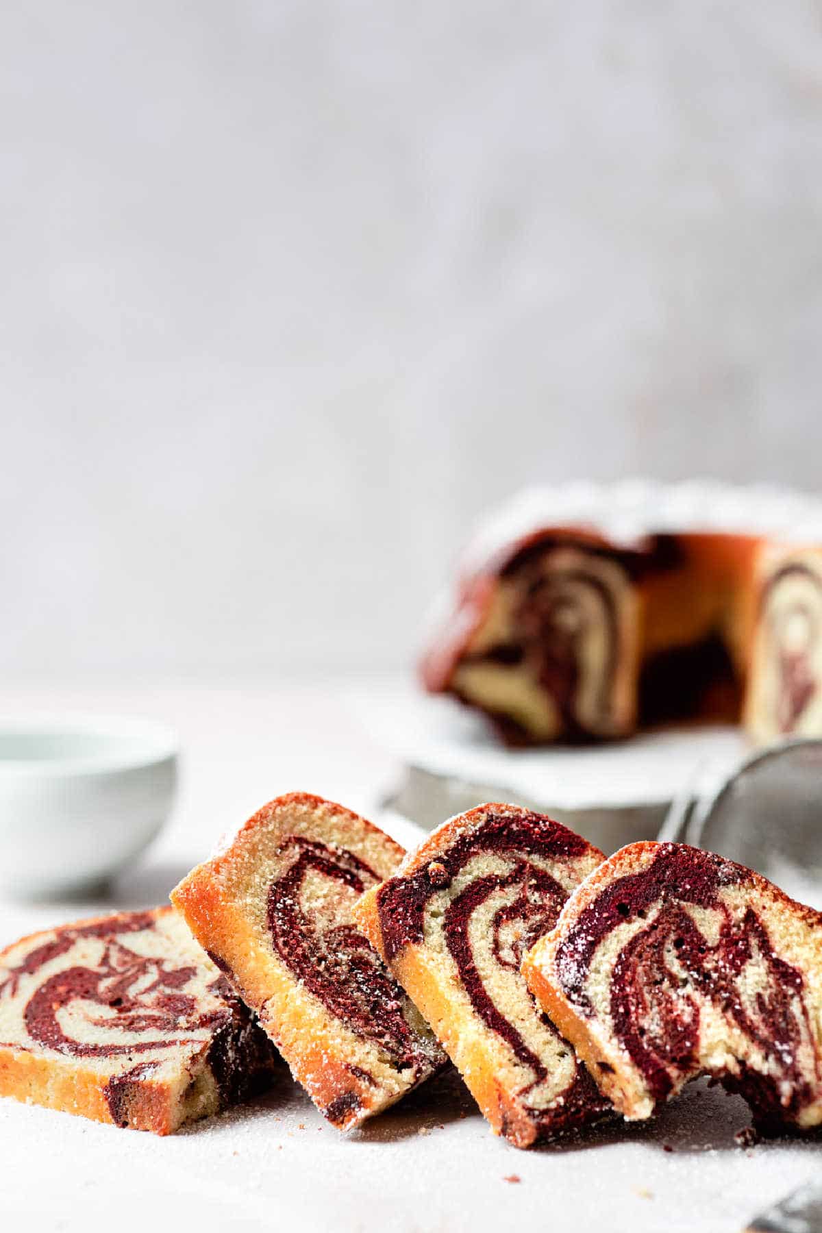 Slices of red velvet cake in front of a bundt cake. 