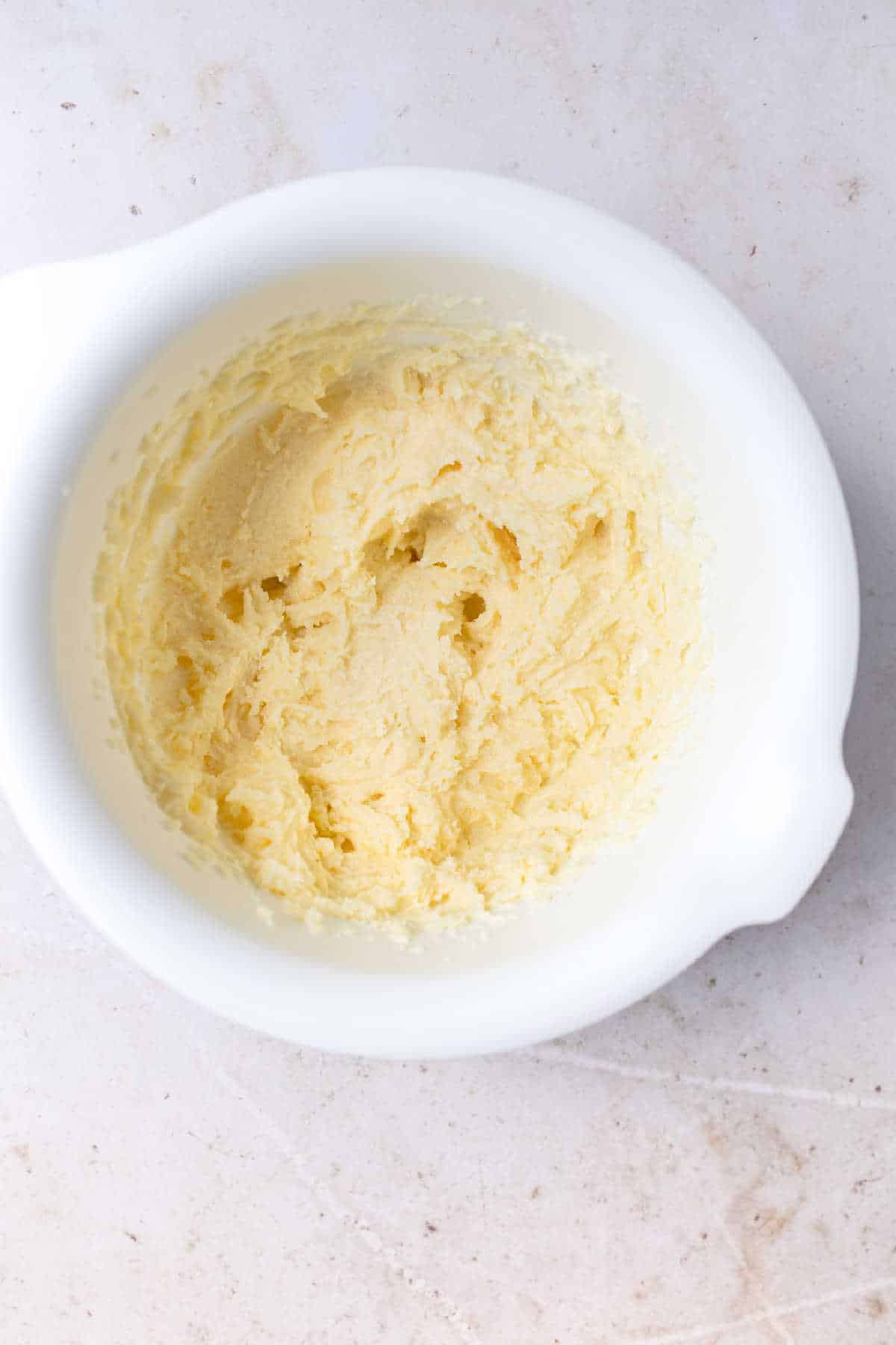 Creamed butter and sugar in a white mixing bowl. 