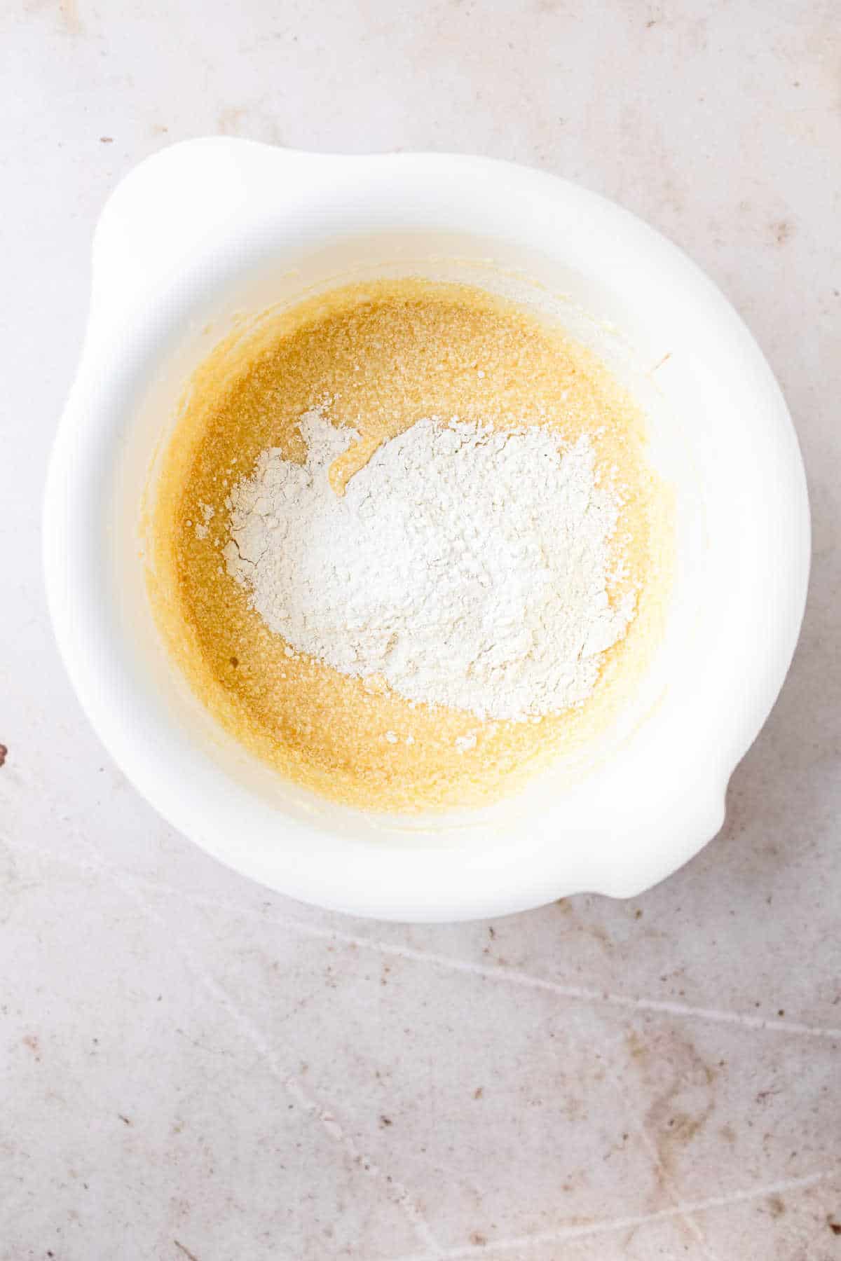 Dry ingredients on wet ingredients in a white mixing bowl.