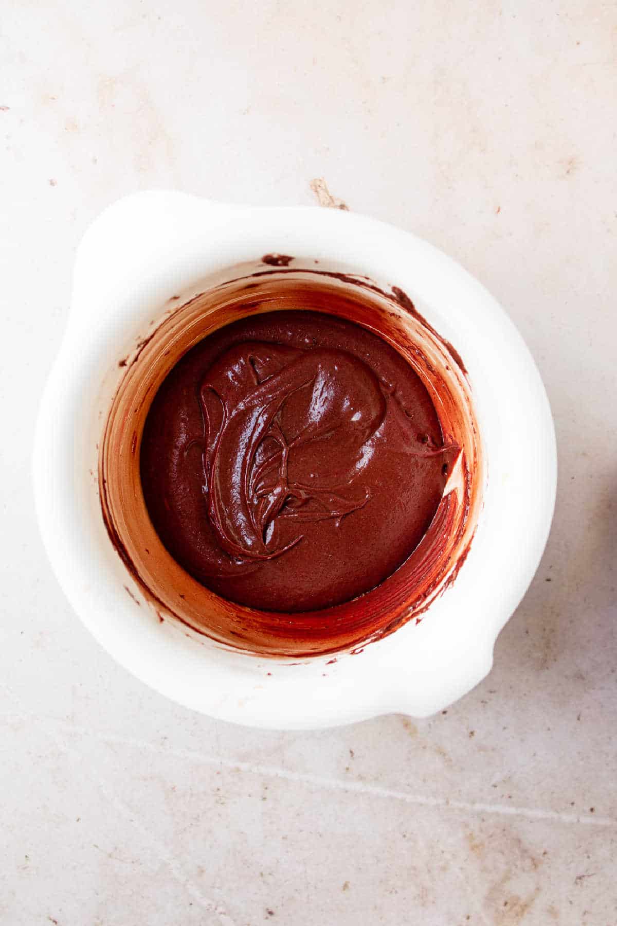 Red velvet cake batter in a white mixing bowl.