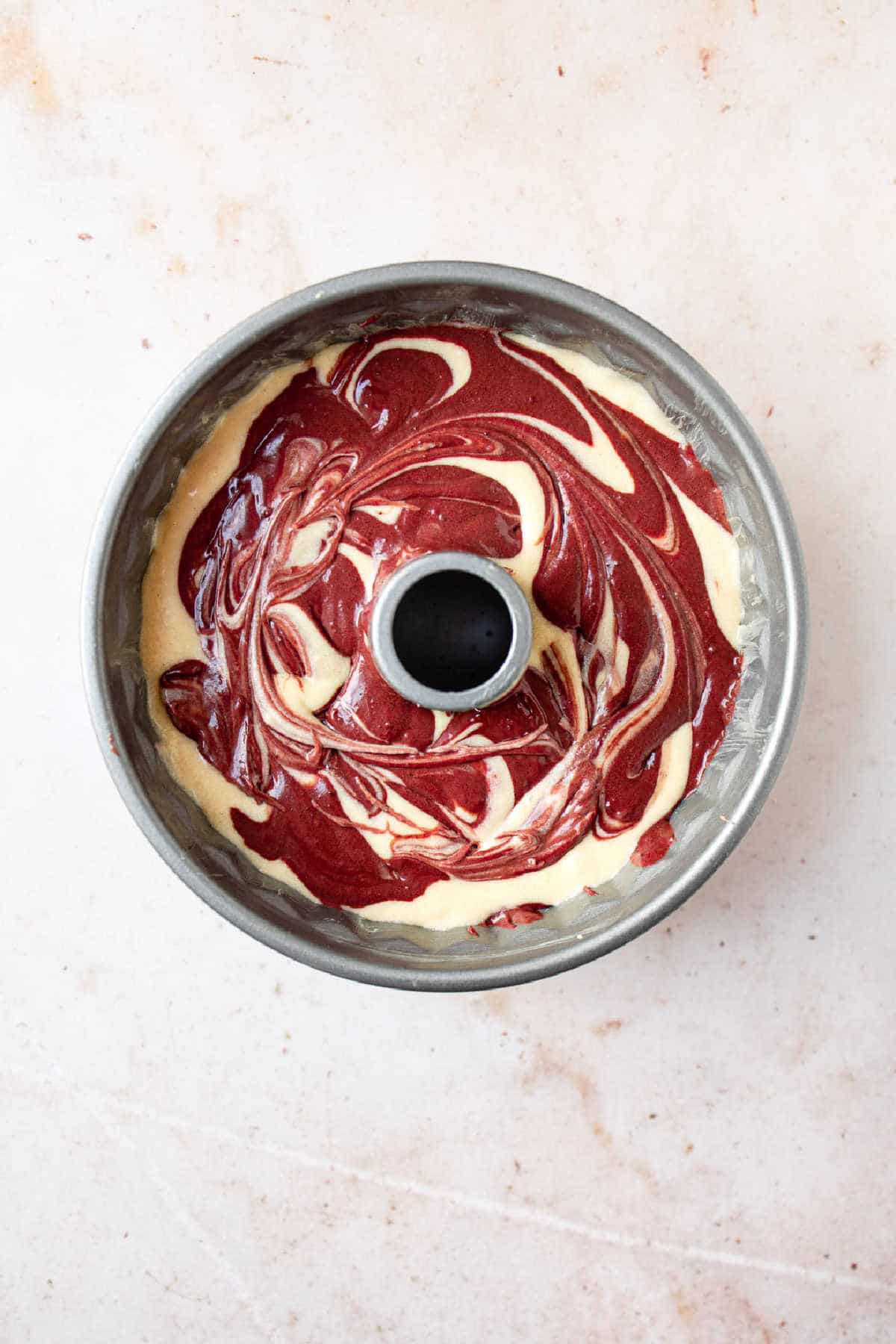 Red velvet marble cake batter in a bundt pan.
