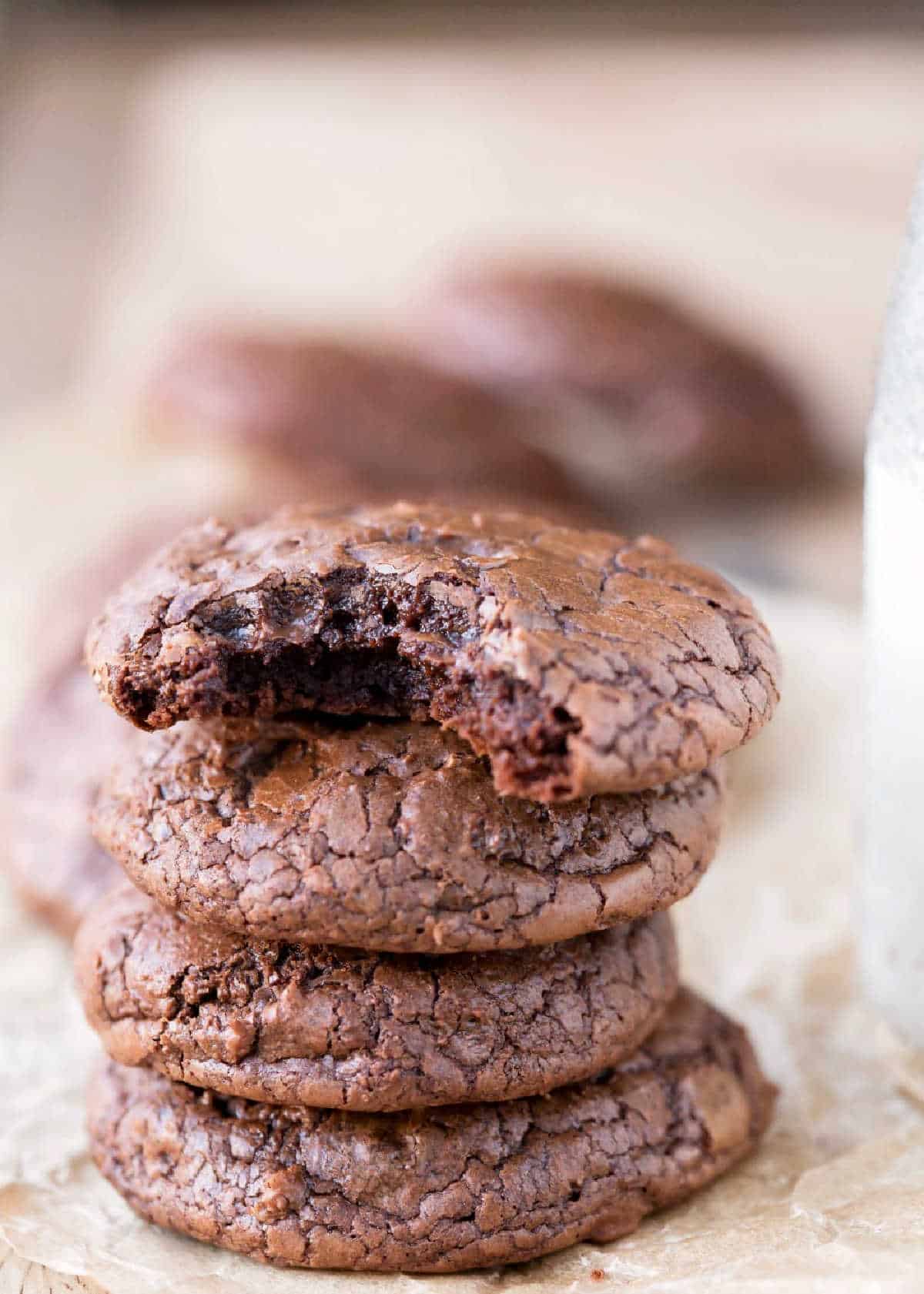Stack of brownie cookies next to a bottle of milk.
