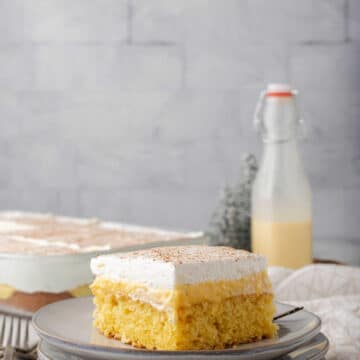 A piece of eggnog poke cake on three plates.