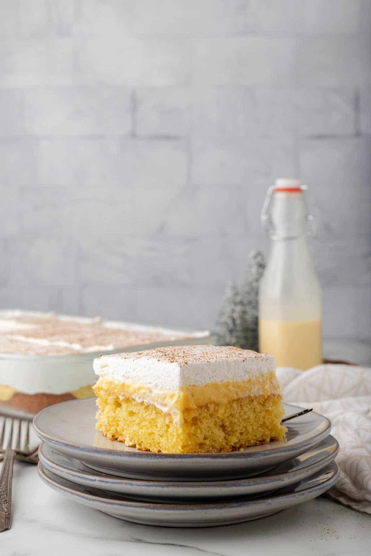 A piece of eggnog poke cake on three plates. 