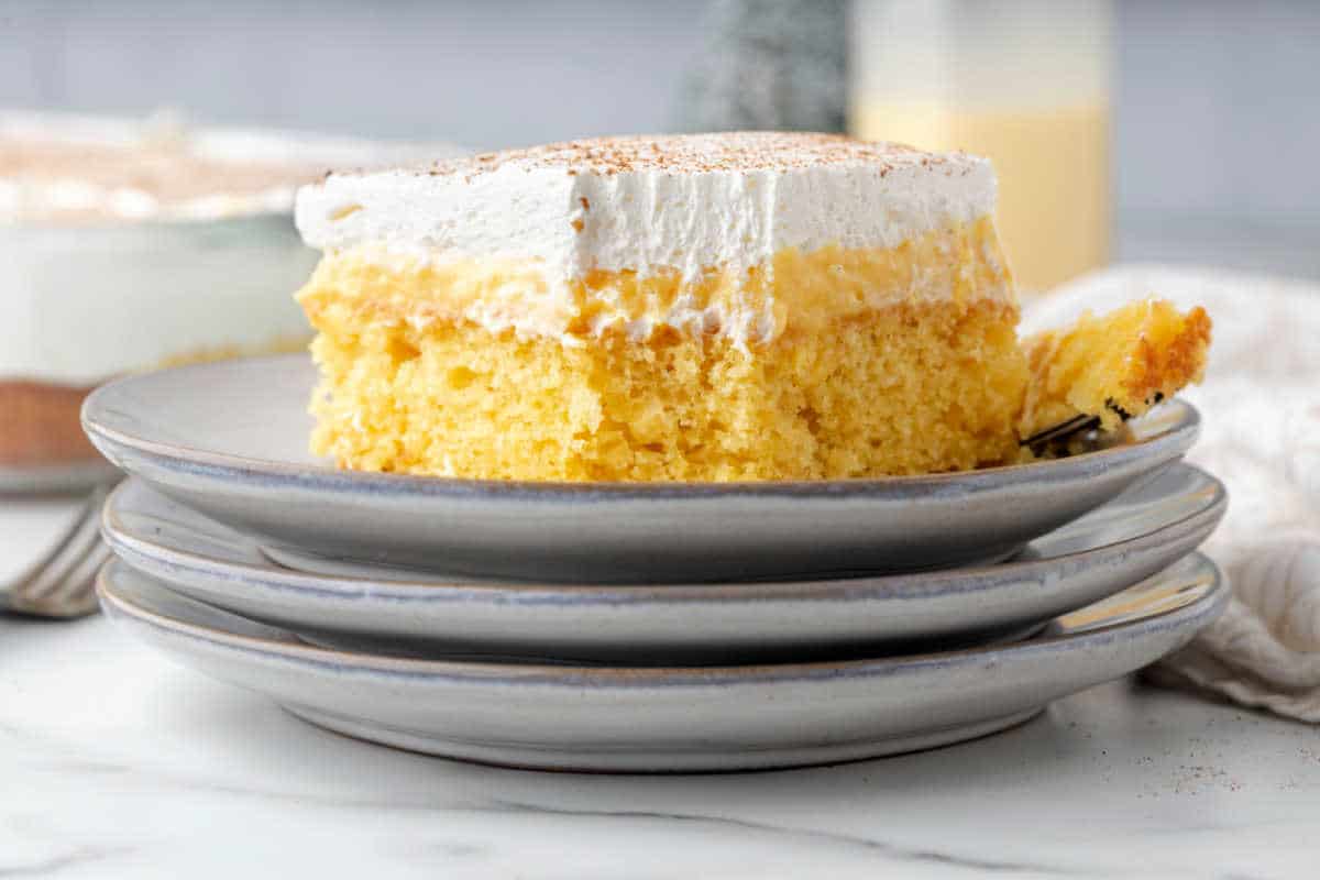 Close shot of a piece of eggnog poke cake with a bite missing. 