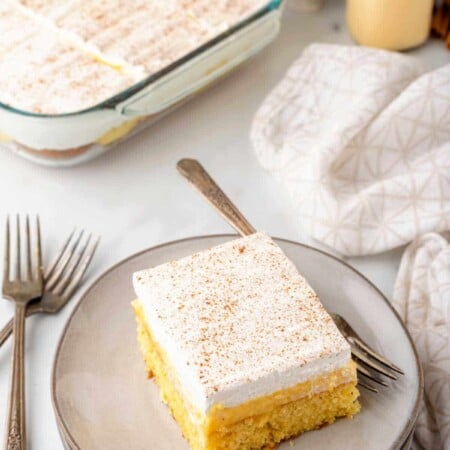 A slice of eggnog poke cake with a fork on the plate.