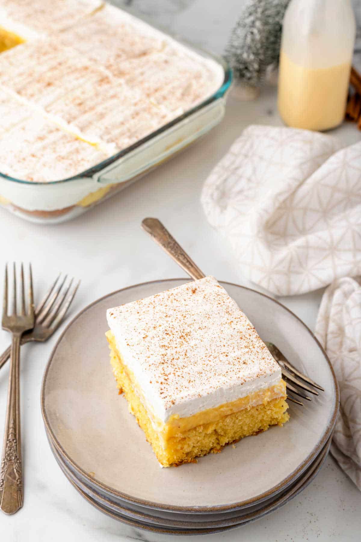 A slice of eggnog poke cake with a fork on the plate. 