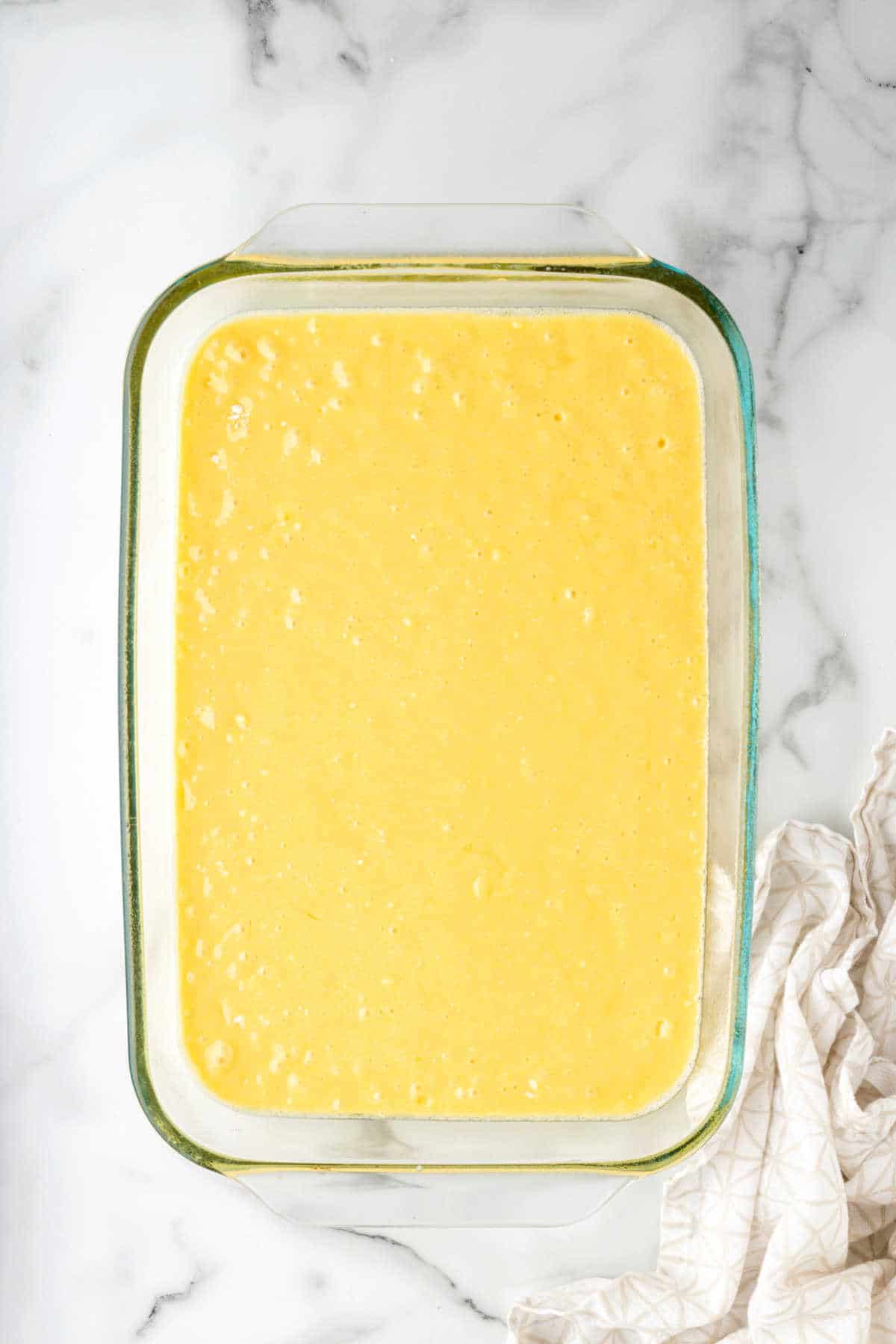Yellow cake batter in a glass baking pan. 