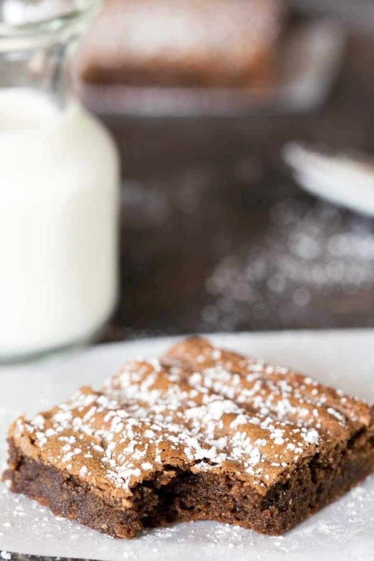 Gingerbread brownie next to a bottle of milk. 