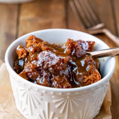 A gold fork taking a bite of gingerbread pudding cake.