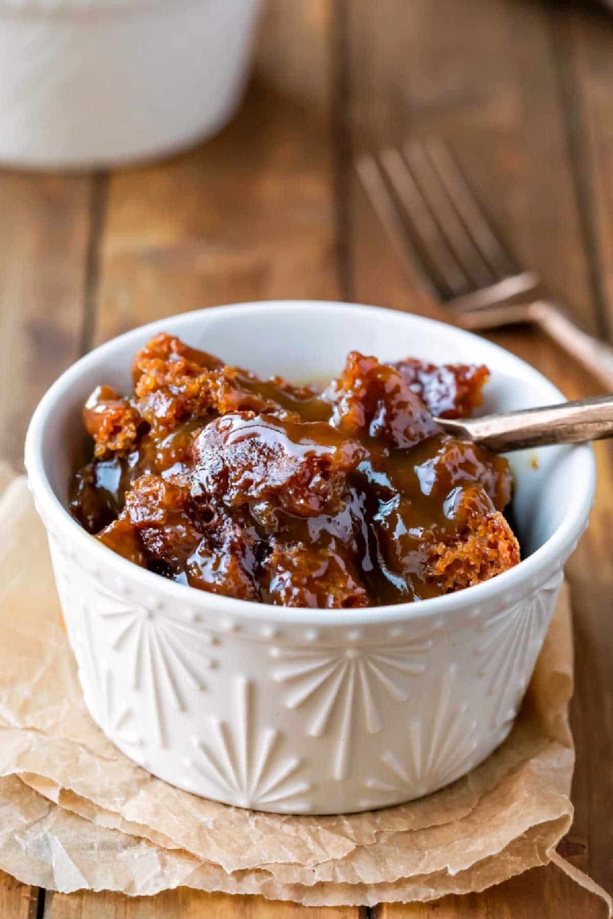 A gold fork taking a bite of gingerbread pudding cake. 