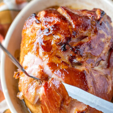Knife and form slicing Maple Glazed Ham in a baking dish