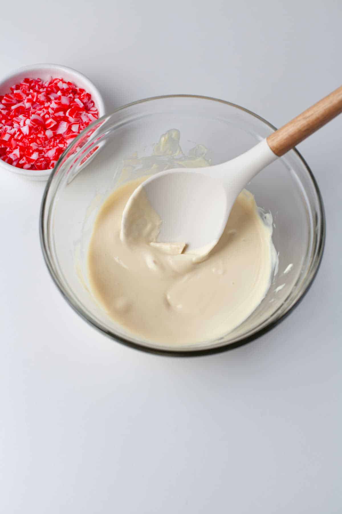Bowl of melted white chocolate with a spoon in it.