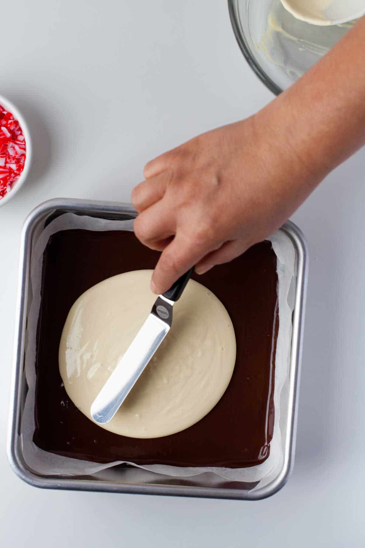An offset spatula smoothing white chocolate over semisweet chocolate. 