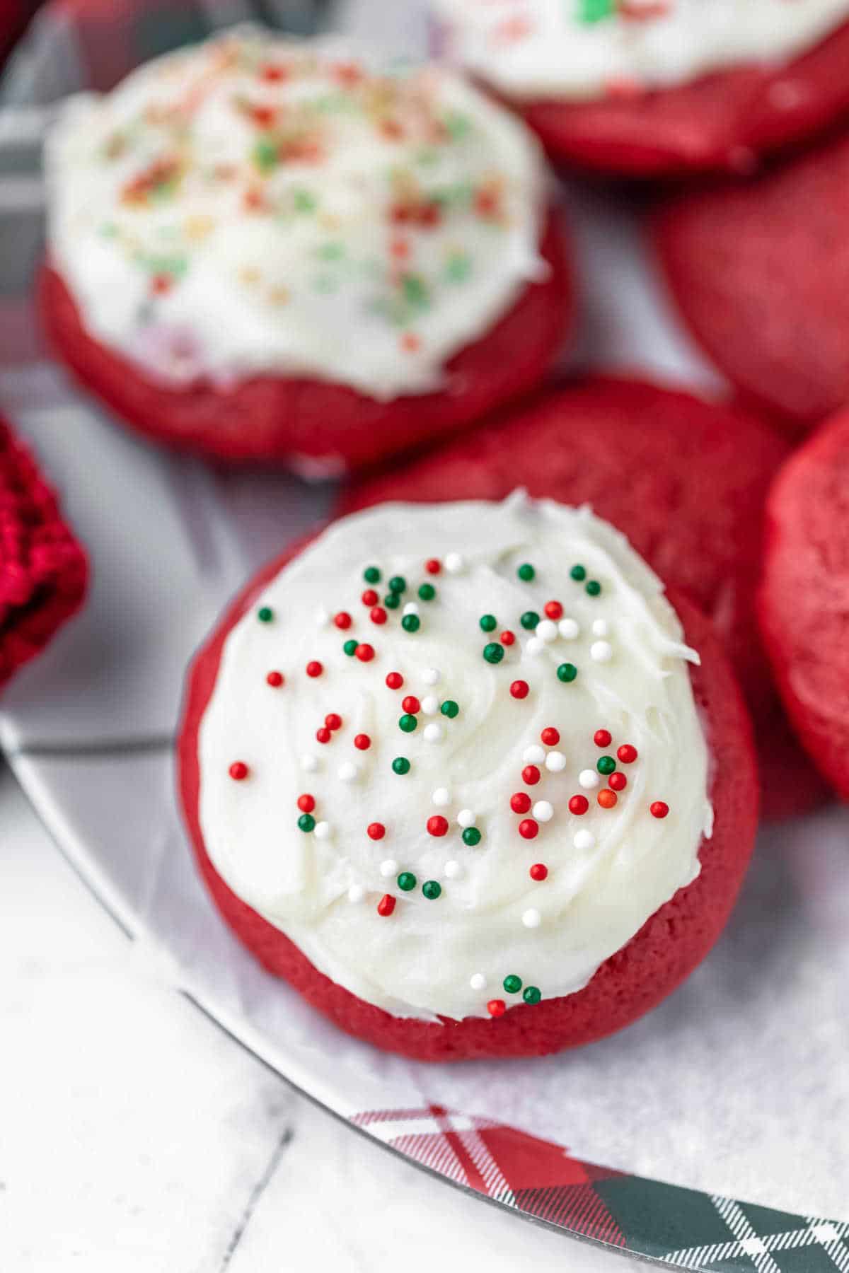 Red velvet cookies with cream cheese frosting on a plaid Christmas plate. 