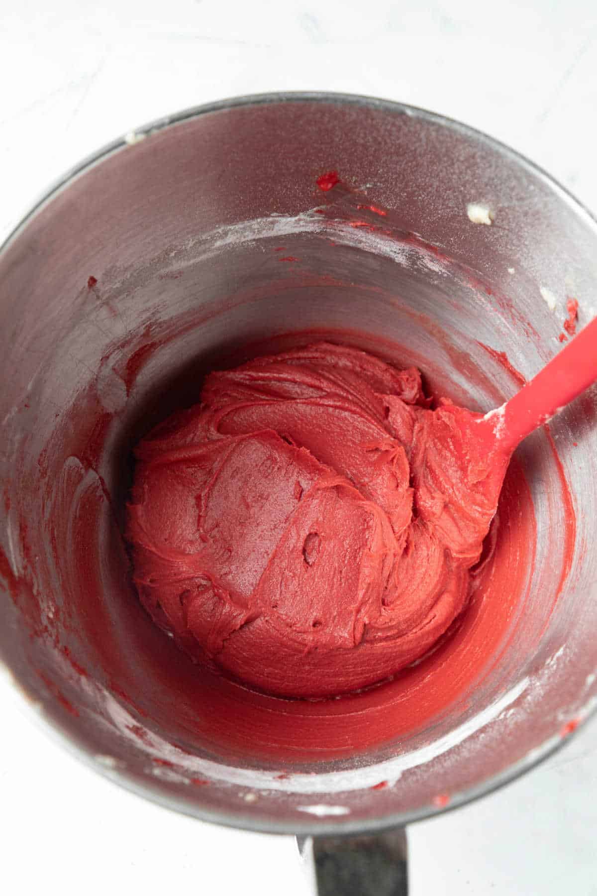 Red velvet cookie dough in a silver mixing bowl. 