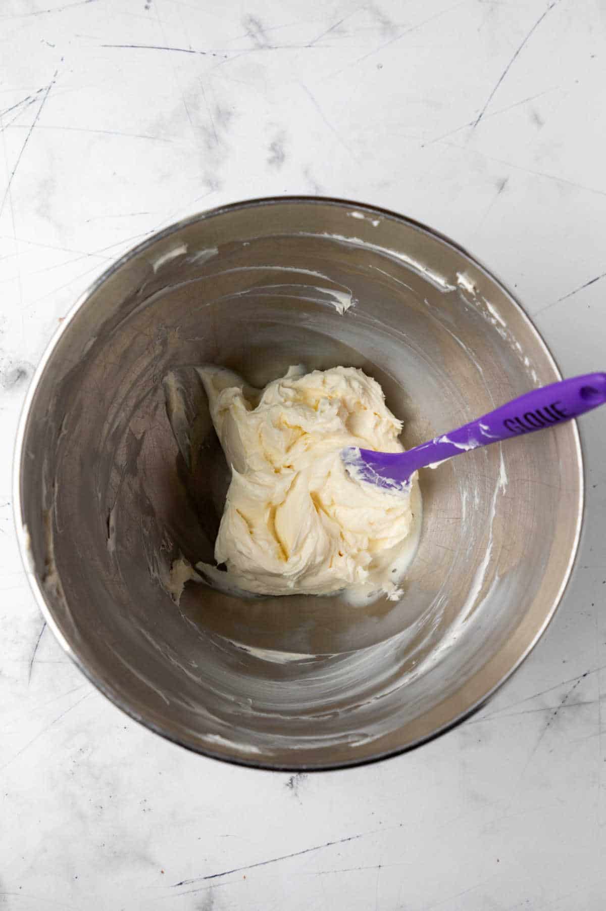 Cream cheese and butter beaten together in a silver mixing bowl. 
