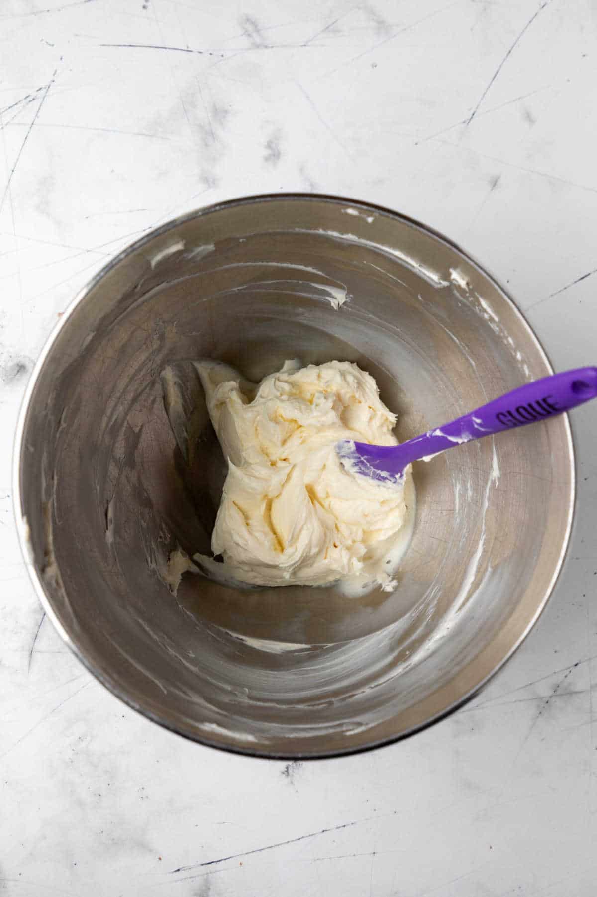 Cream cheese and butter beaten together in a silver mixing bowl.