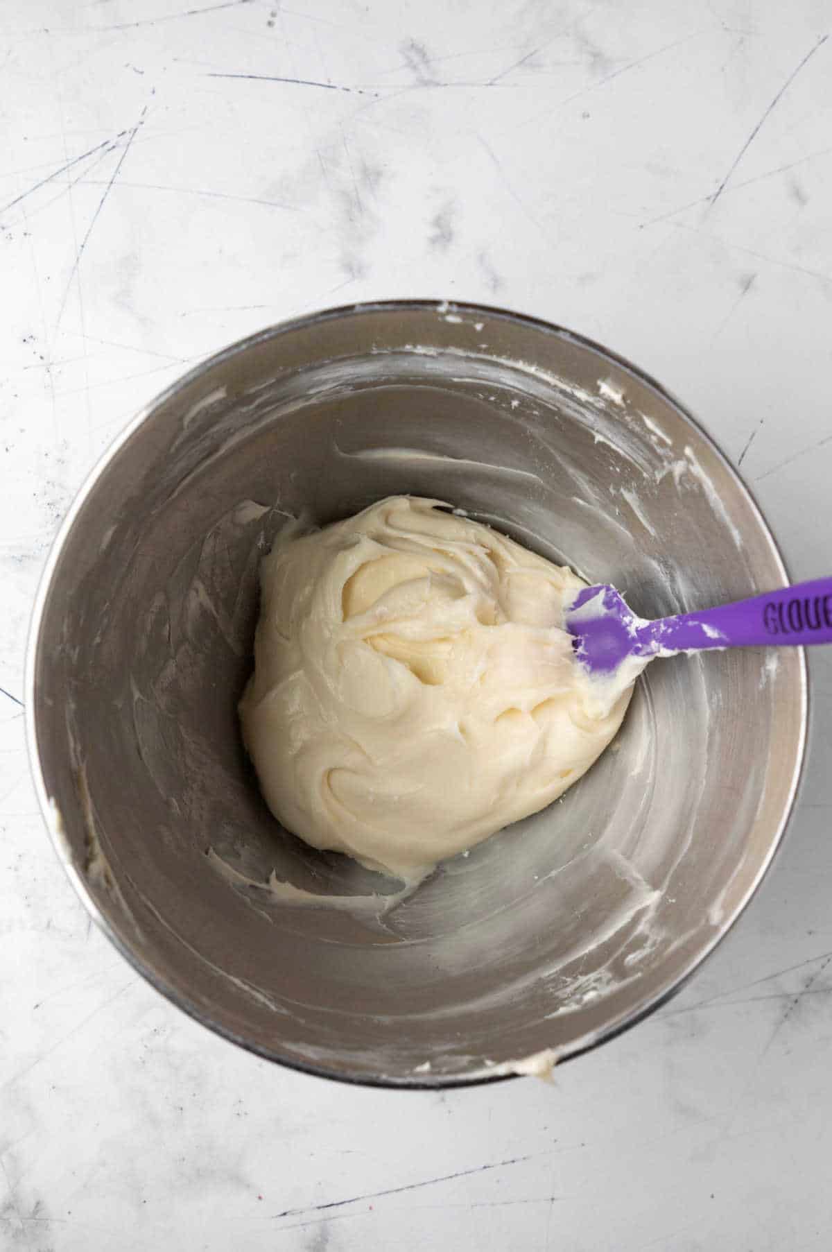 Cream cheese frosting in a silver mixing bowl. 