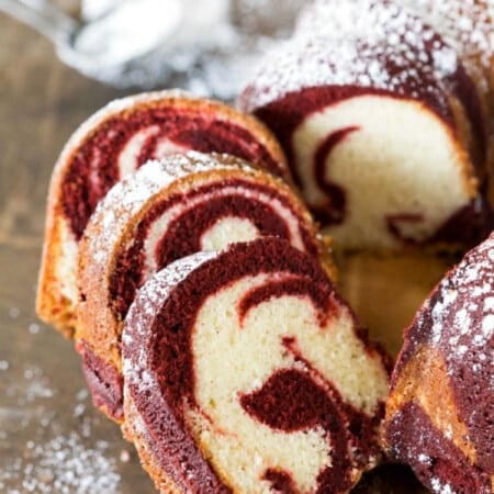 Slices of red velvet marble cake on a wooden serving platter.