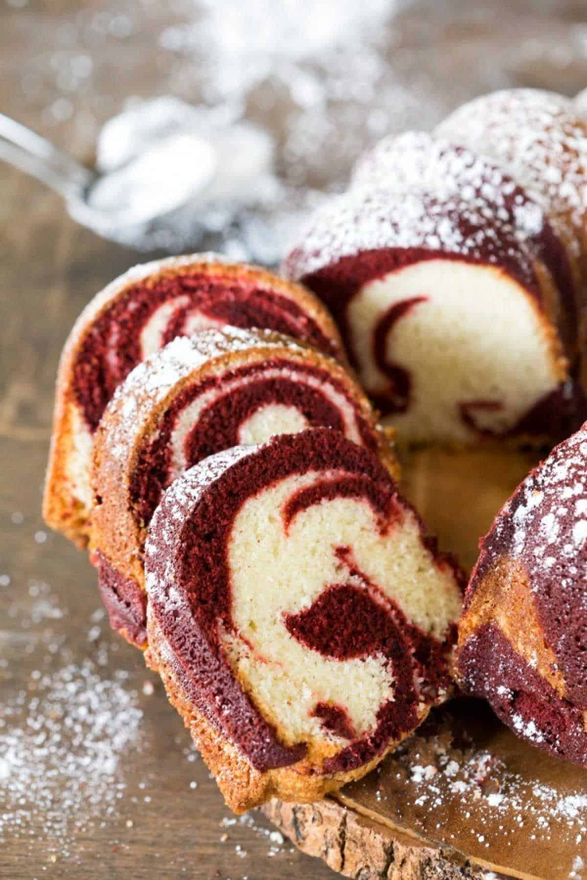 Slices of red velvet marble cake on a wooden serving platter.