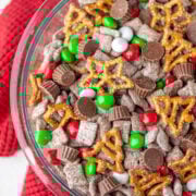 A glass bowl with reindeer chow on a red knit towel.