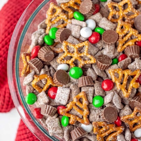 A glass bowl with reindeer chow on a red knit towel.