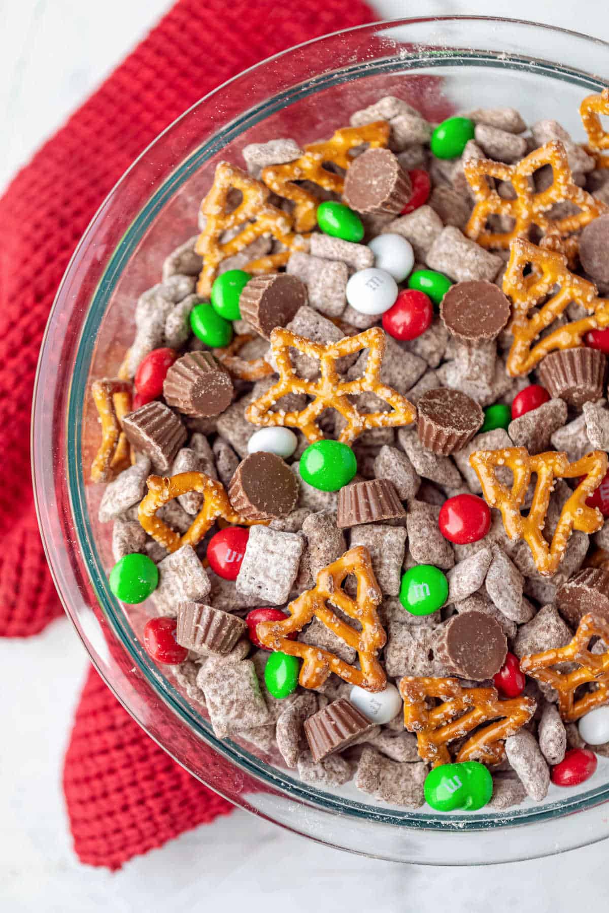 A glass bowl with reindeer chow on a red knit towel.