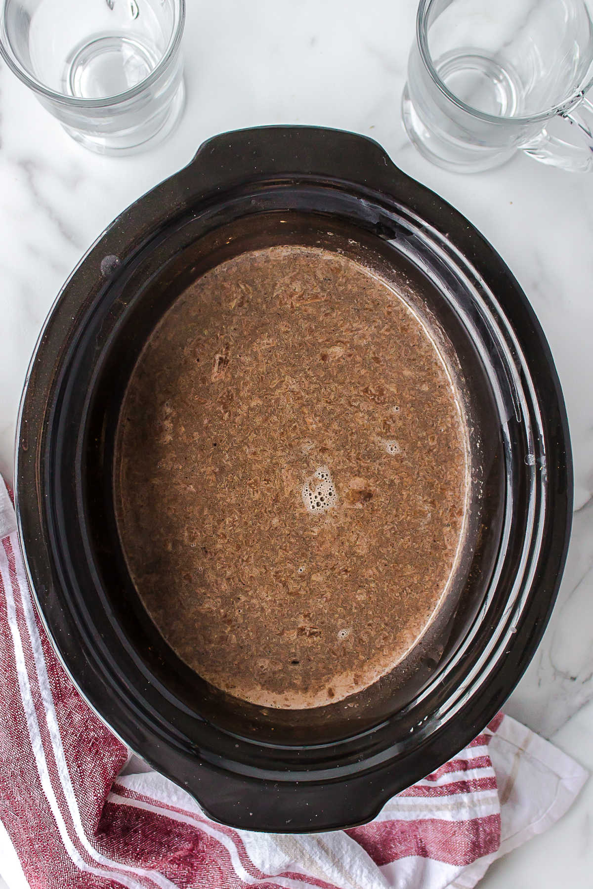 Ingredients for slow cooker hot chocolate stirred together in a slow cooker insert.