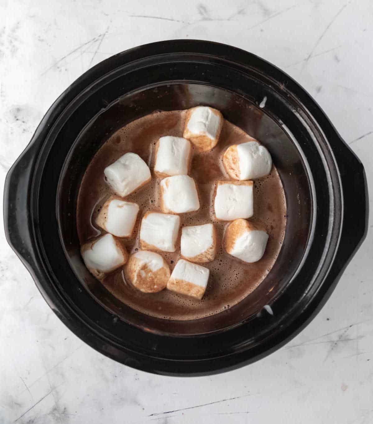 Slow cooker insert full of hot chocolate and marshmallows.
