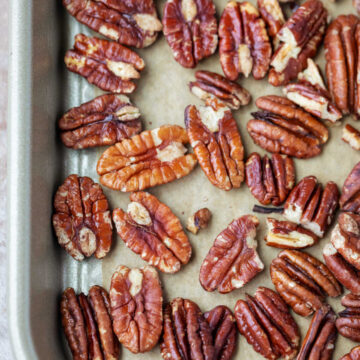 Rimmed baking sheet with toasted pecans on it.