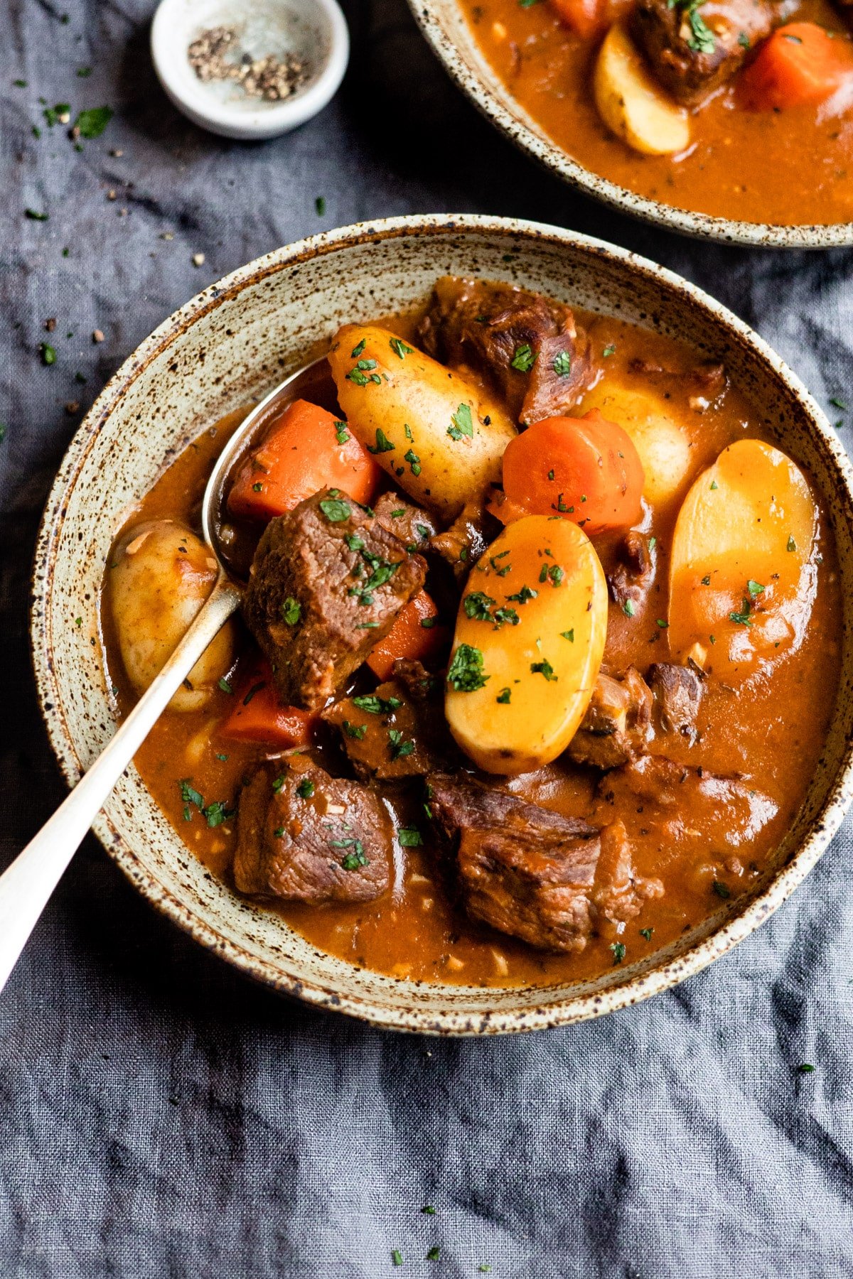 Bowl of beef stew topped with parsley.