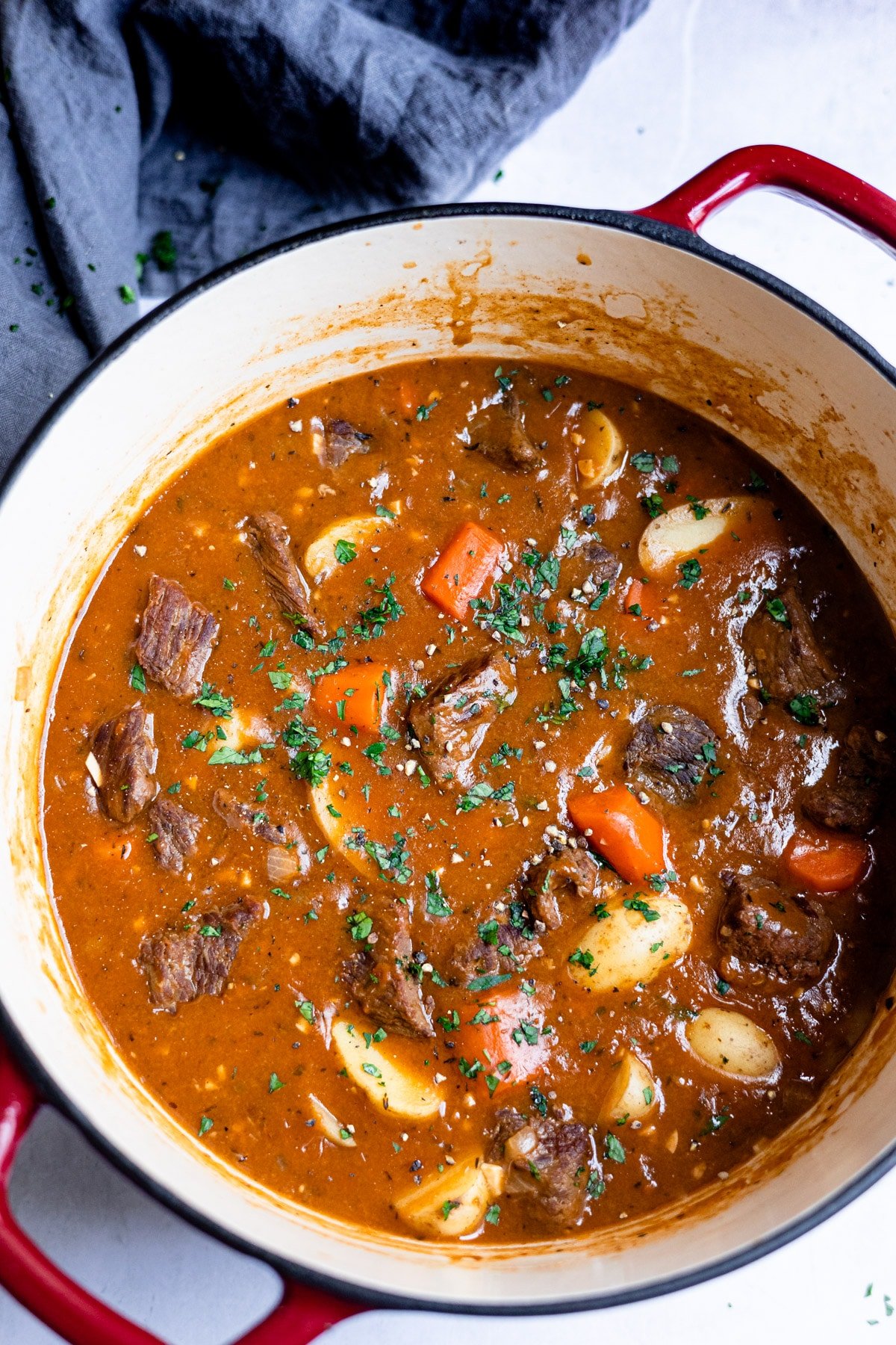 Pot of Dutch oven beef stew on a blue linen. 