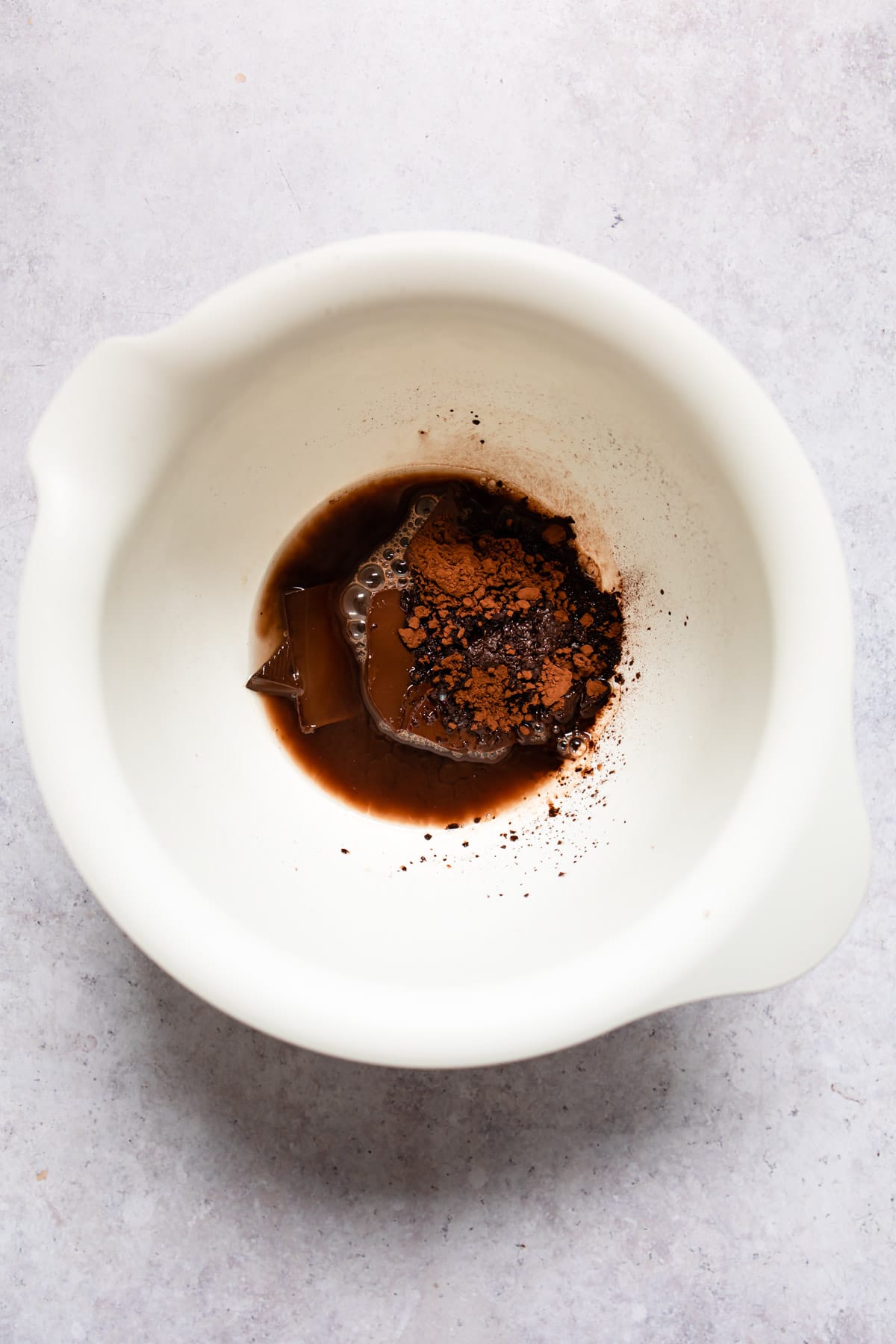 Boiling water cocoa powder and chocolate in a white mixing bowl. 