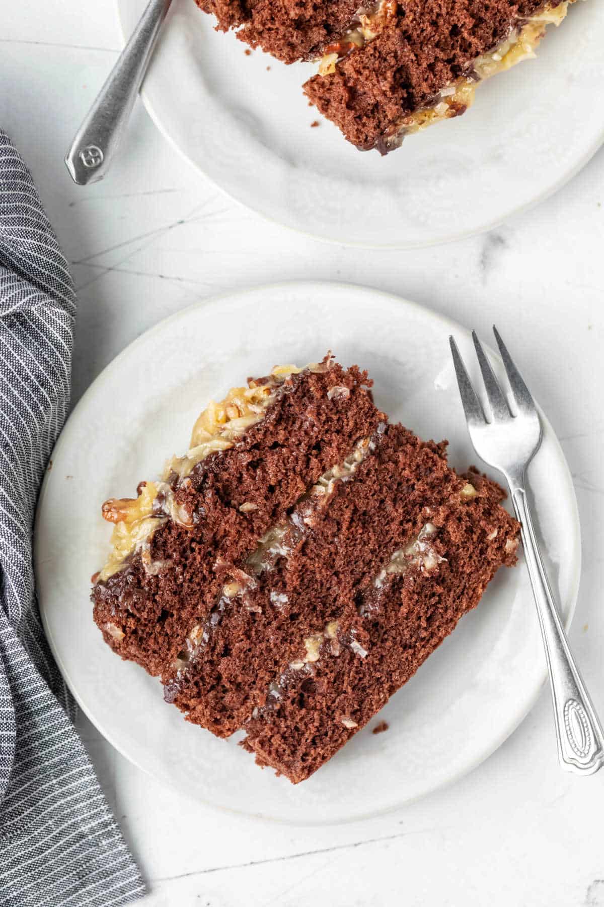 Two white plates with slices of german chocolate cake on them. 