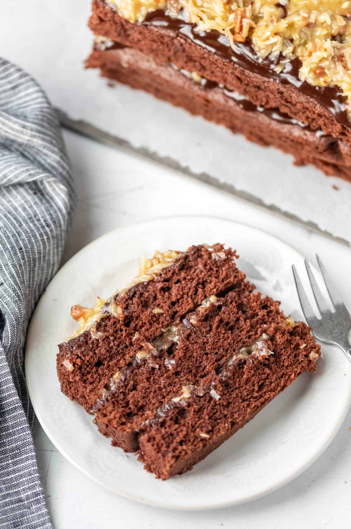 Slice of homemade German chocolate cake next to the entire cake. 