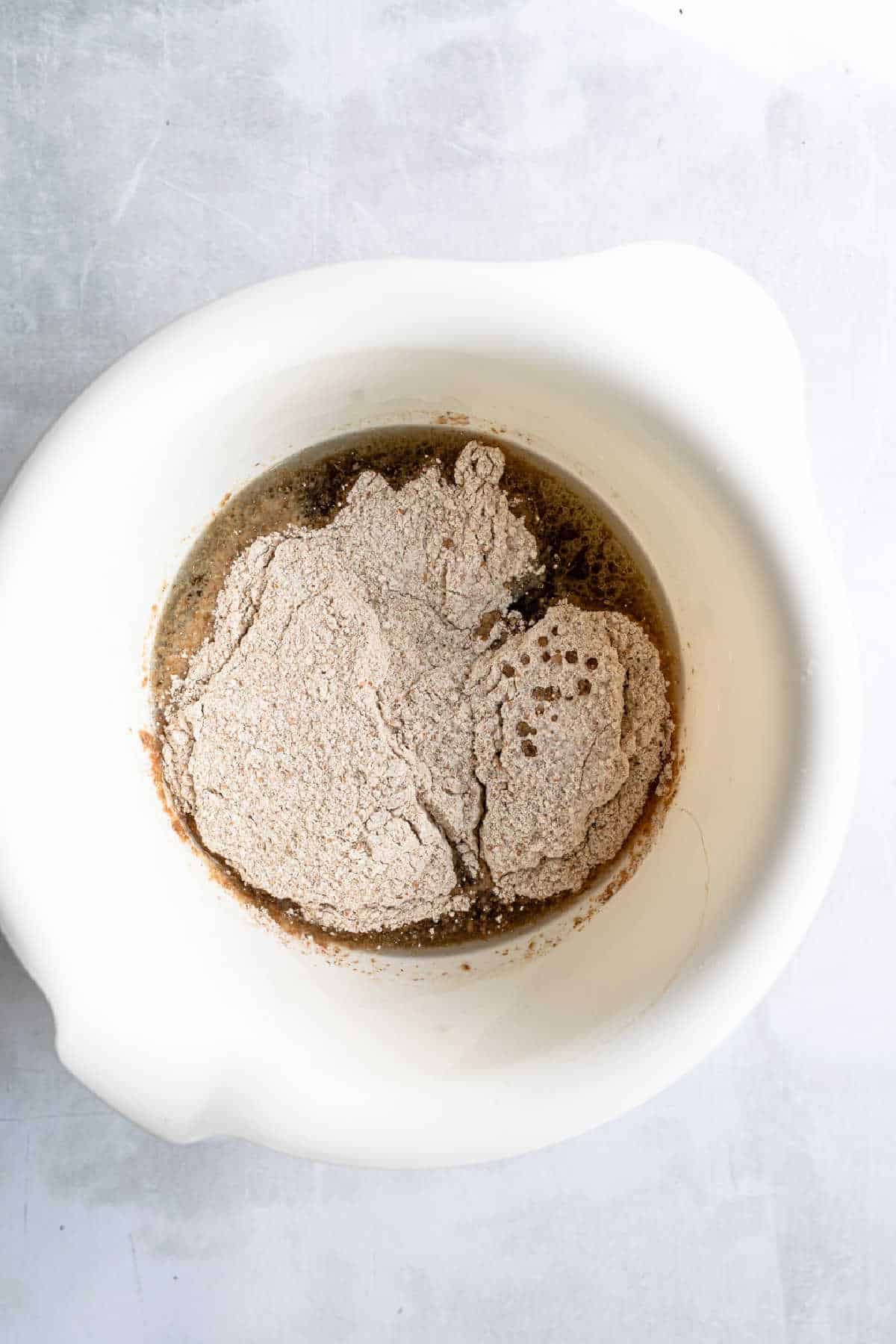 Wet and dry ingredients for outback bread in a white mixing bowl. 