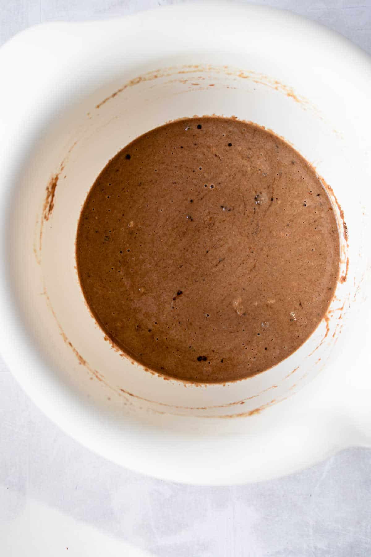 Wet and dry ingredients for outback bread stirred together in a white mixing bowl. 