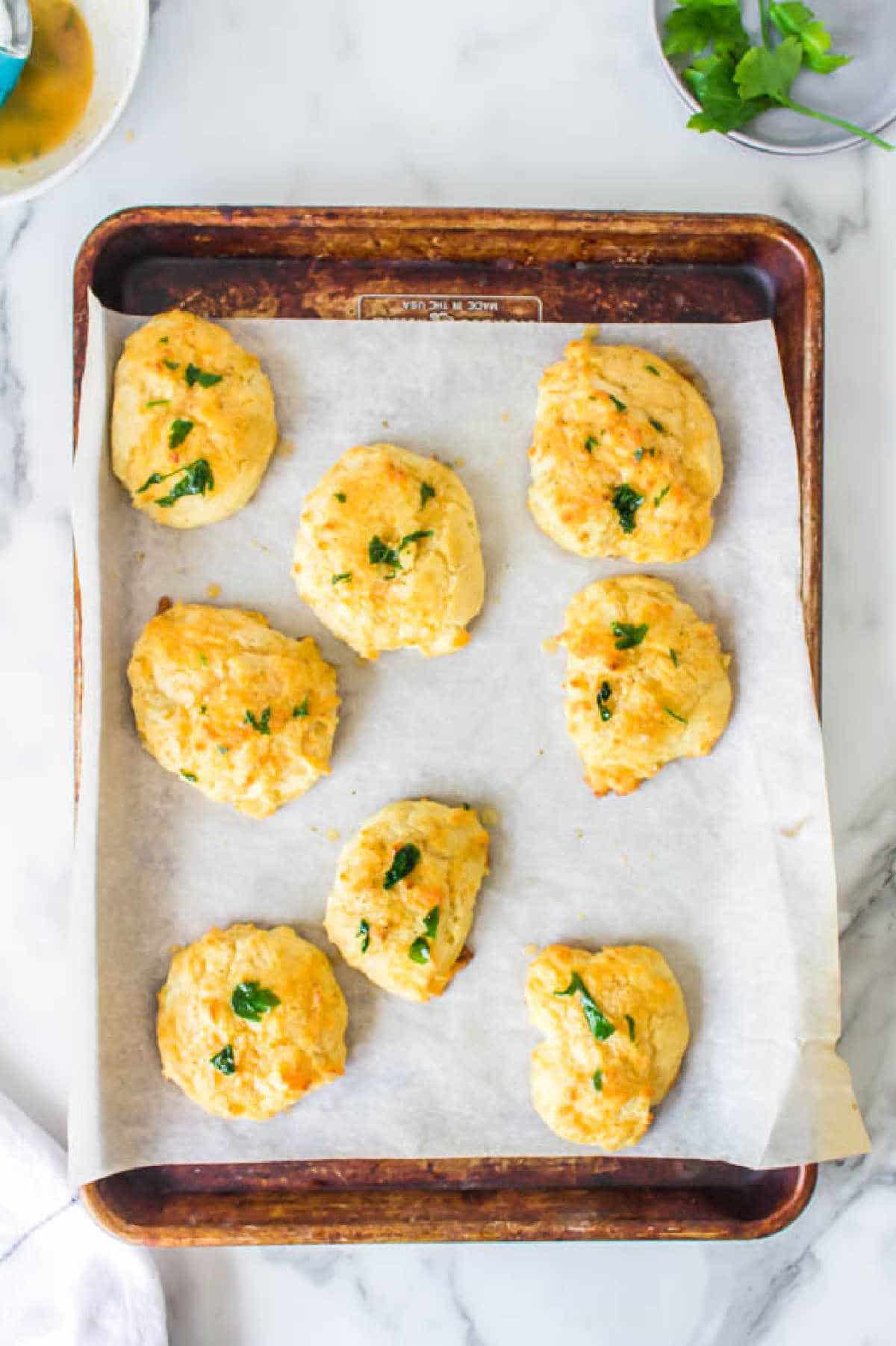 Cheddar bay biscuits on a baking sheet. 