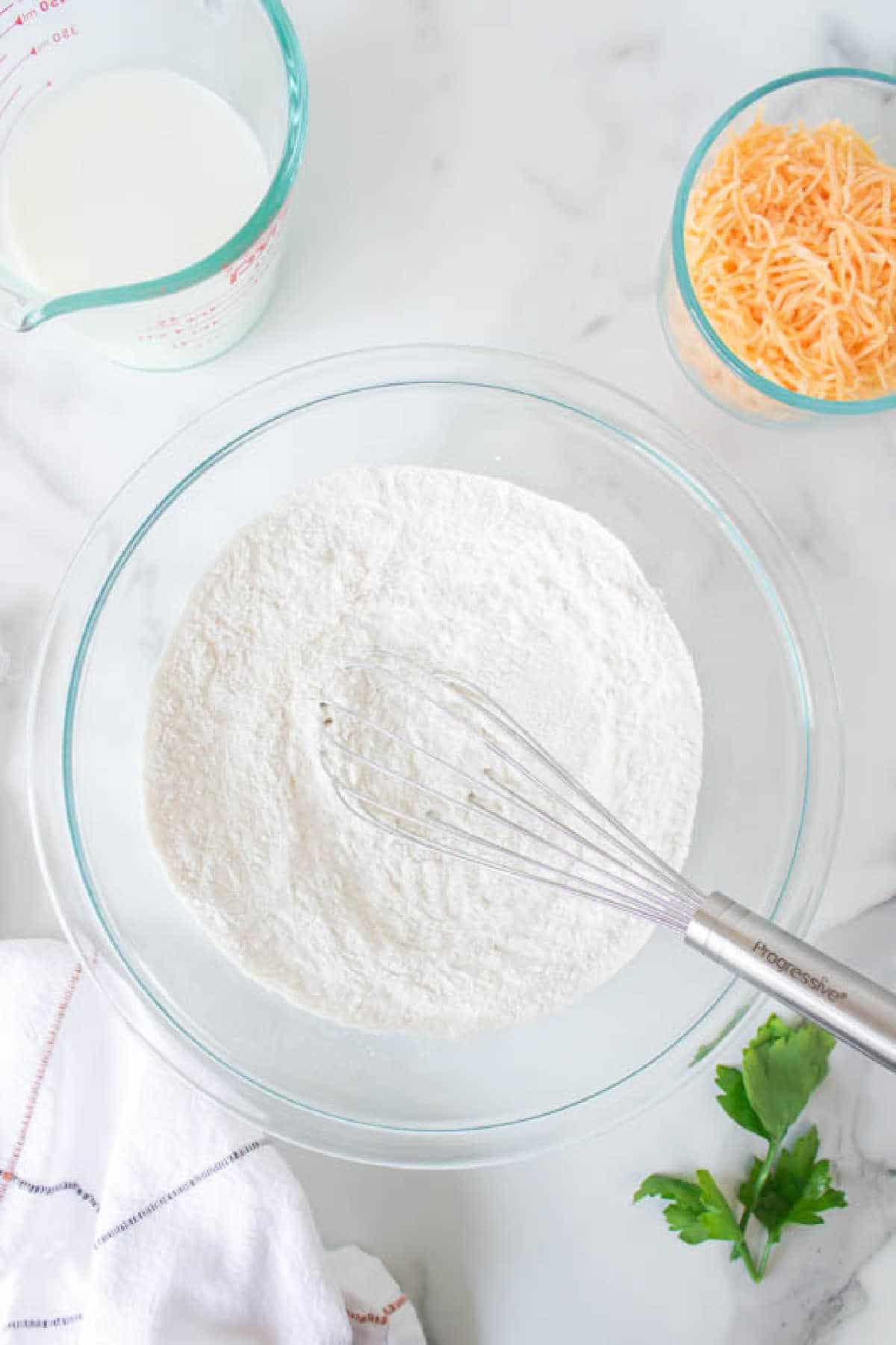 Dry ingredients for cheddar bay biscuits in a glass mixing bowl. 