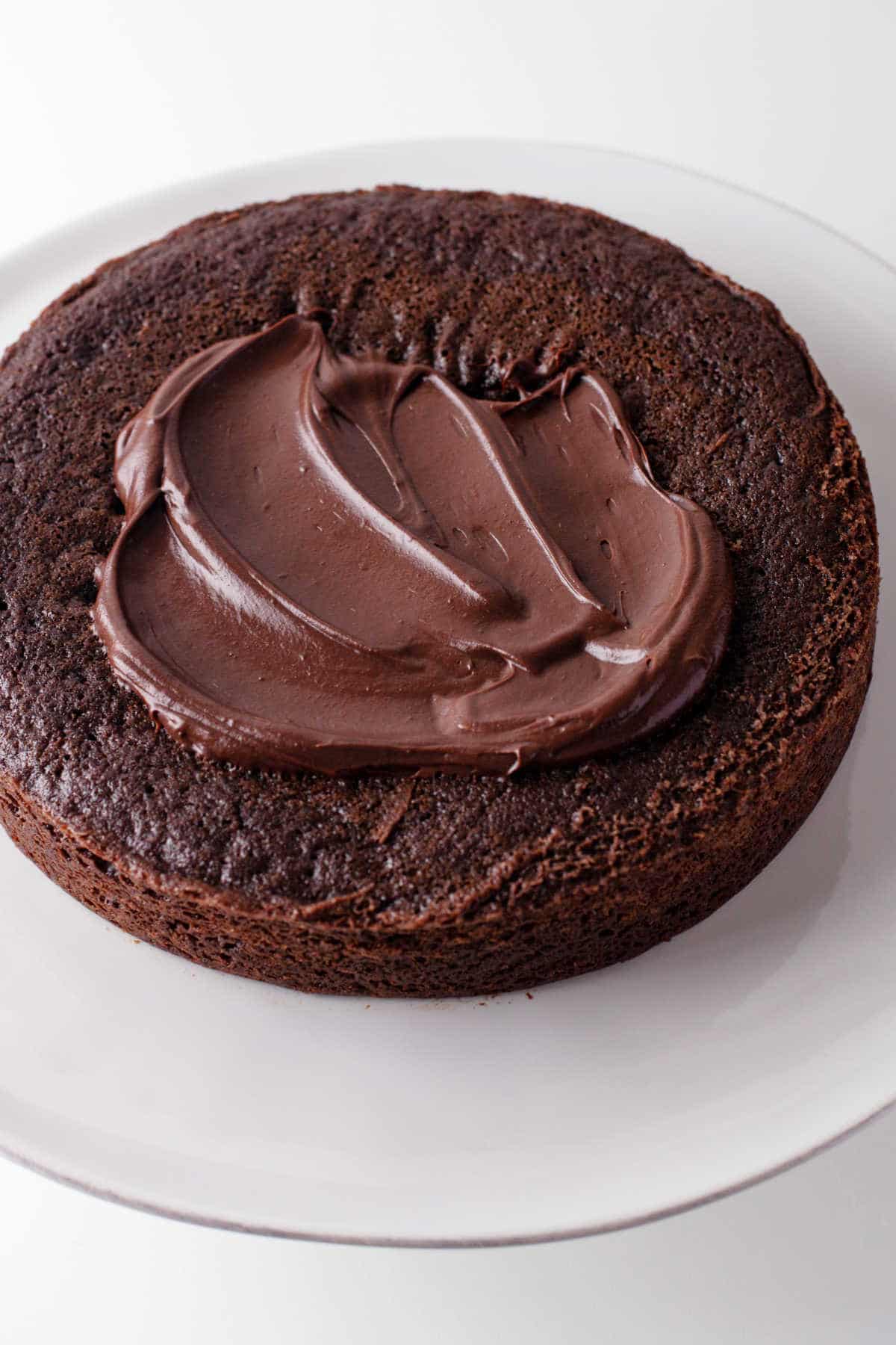 A chocolate cake layer partially spread with chocolate ganache. 