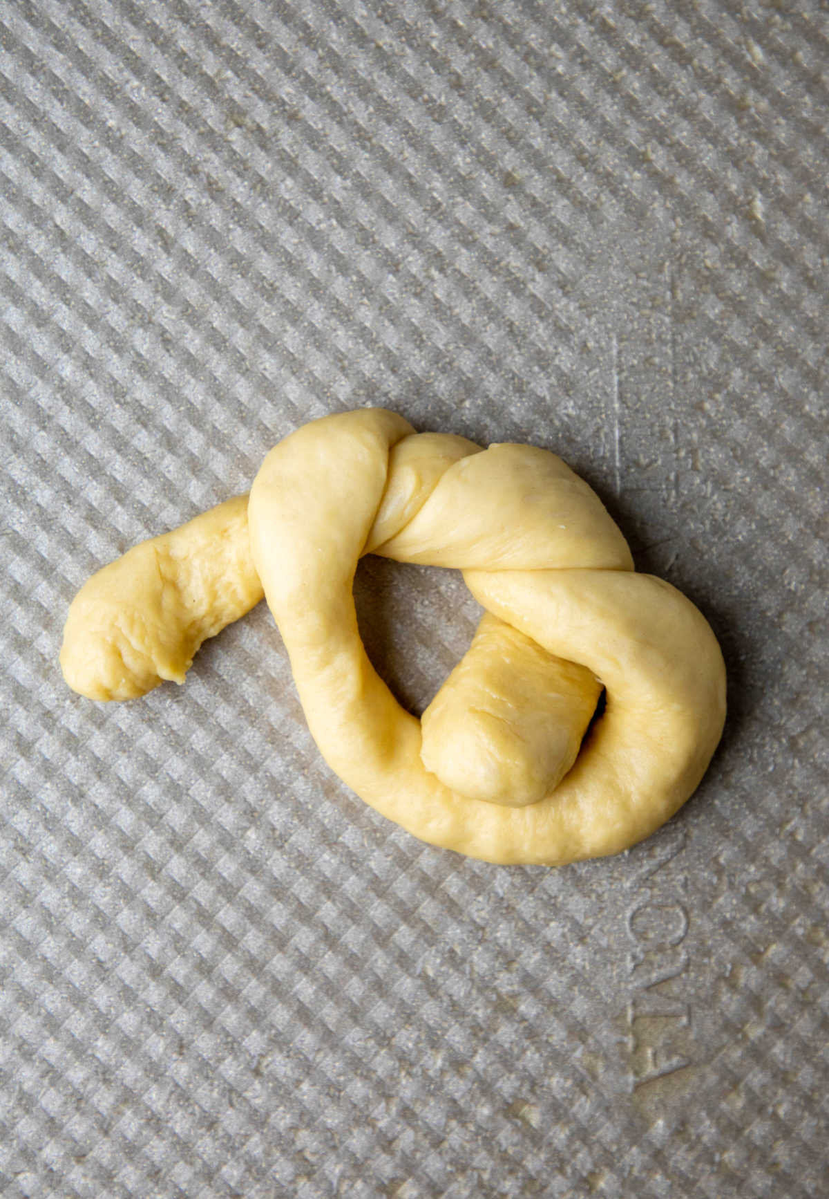 Piece of dough  being tied into a fancy knot. 