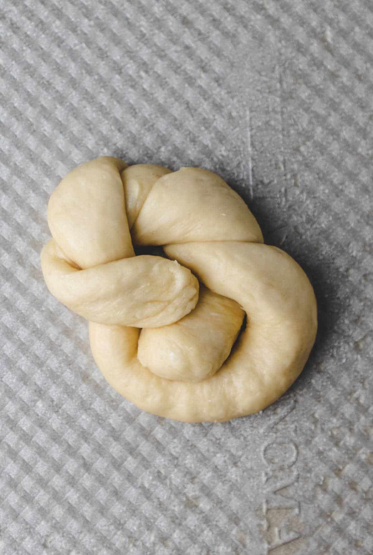 Unbaked garlic knot on a baking tray.