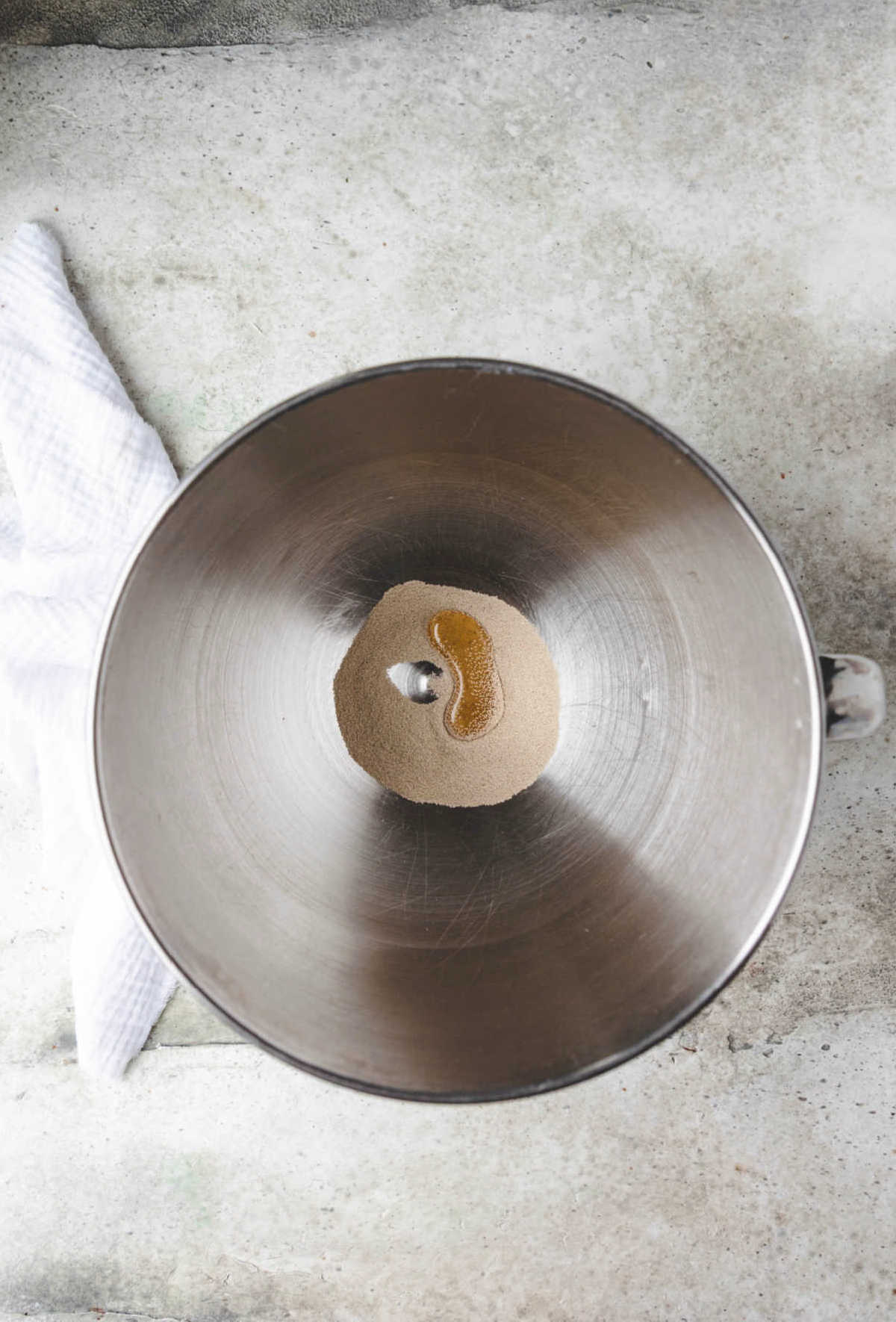 Yeast and honey in a silver mixing bowl. 