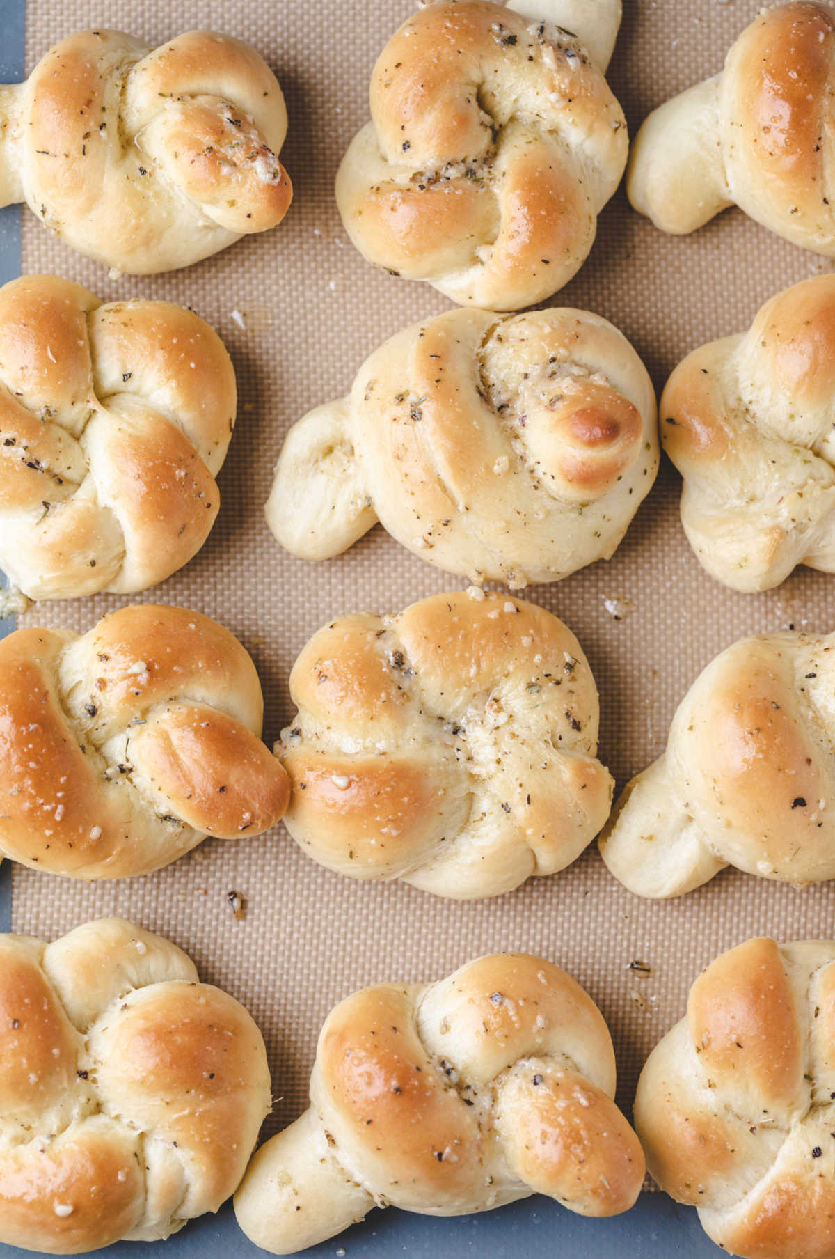 Baked garlic knots on a silicone baking mat. 