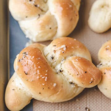 Close up photo of a garlic knot on a baking sheet.