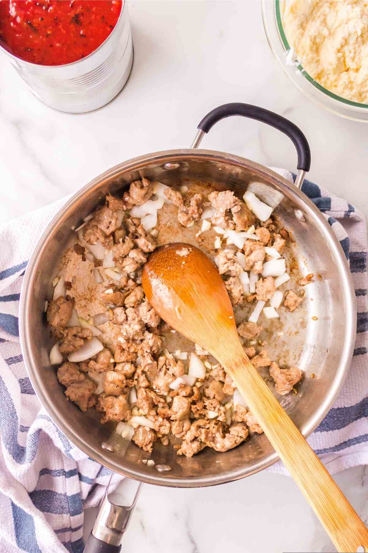 Italian sausage garlic and onion in a silver skillet. 